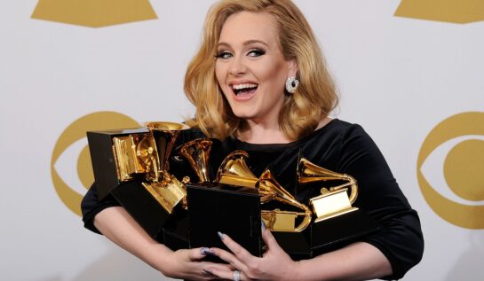 Cântăreața Adele în timp ce ține în mână șase premii muzicale în anul 2012
