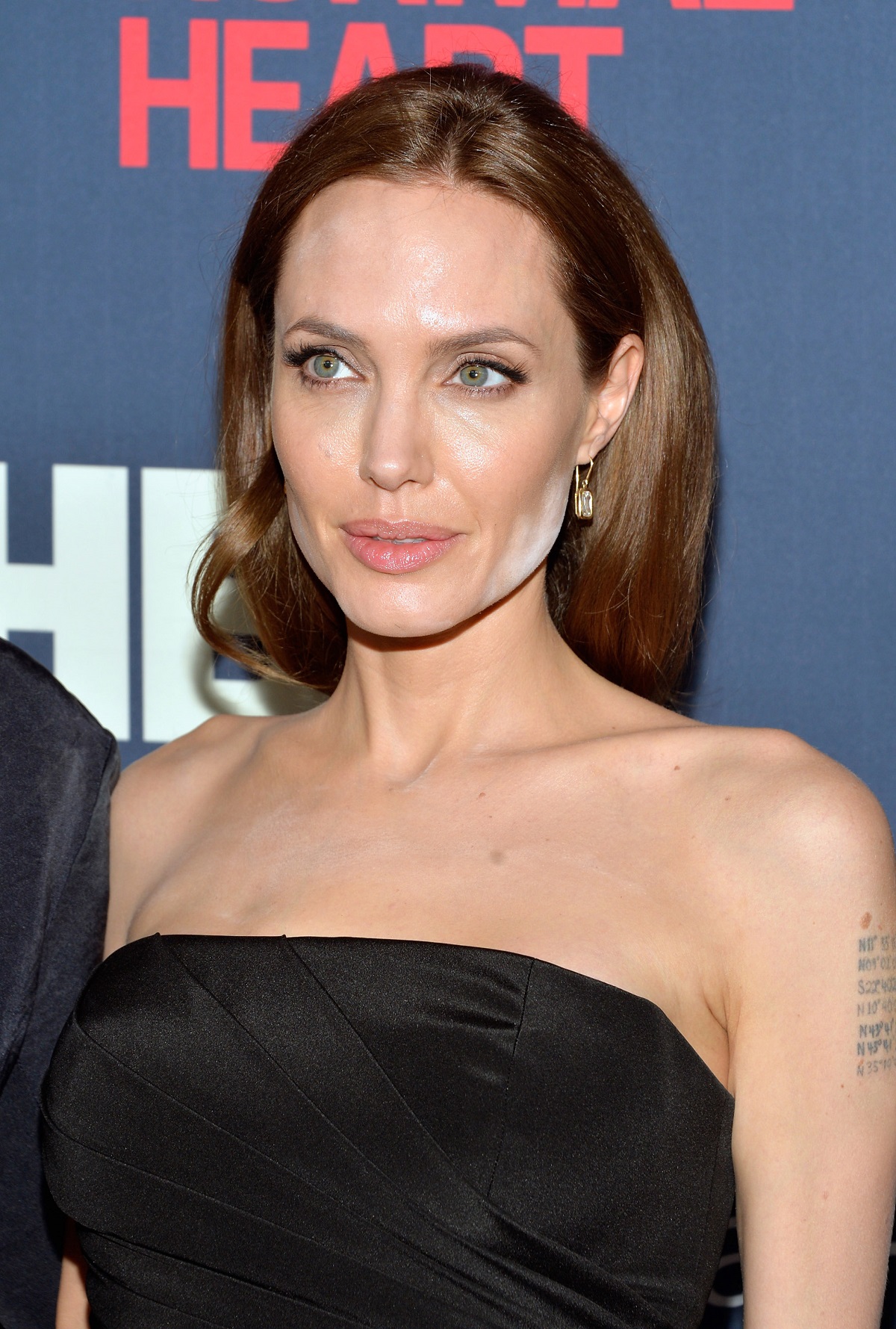 Angelina Jolie cu pudră albă pe față și pe decolteu pe covorul roșu alături de Brad Pitt în 2014