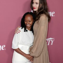 Angelina Jolie într-o rochie maro în timp ce o ține în brațe pe fiica sa, Zahara Jolie-Pitt