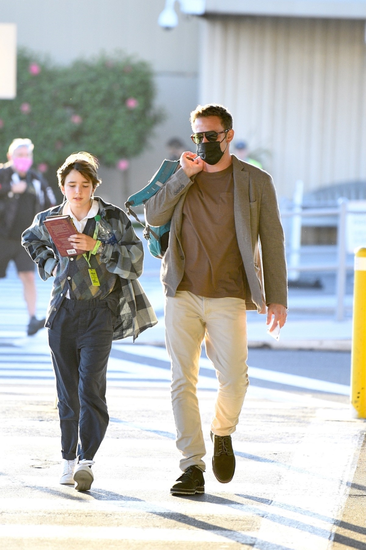 Ben Affleck într-o pereche de pantaloni crem și un tricou bej în timp ce vine de la aeroportul din Los Angeles alături de fiica sa, Seraphina