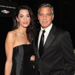 George și Amal Clooney, 2014, la Celebrity Fight Night. Amândoi sunt îmbrăcați în negru. George poartă un costum negru, cu o cămașă albă și o cravată neagră. Amal poartă o rochie neagră fără bretele