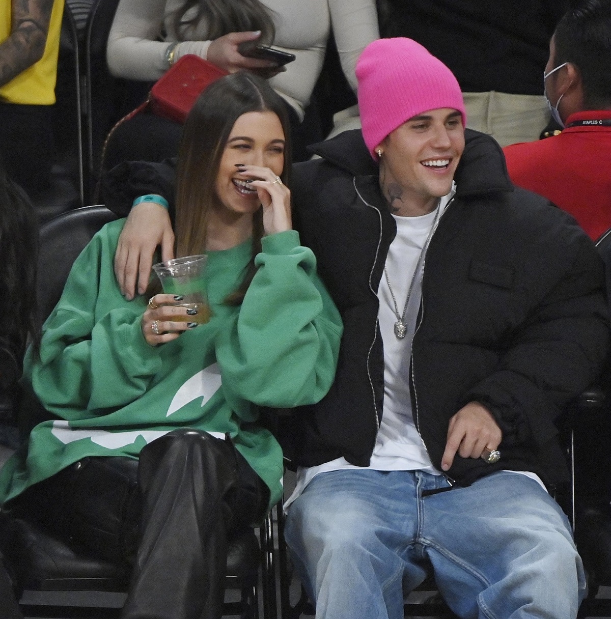 Hailey Bieber într-un hanorac verde și Justin Bieber în ipostaze tandre la un meci de baschet