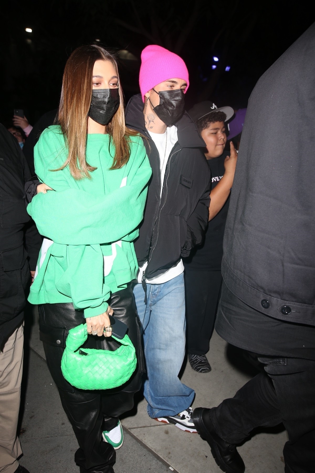Hailey Bieber într-un hanorac verde în timp ce merge lângă Justin Bieber după ce au fost la un meci de baschet împreună
