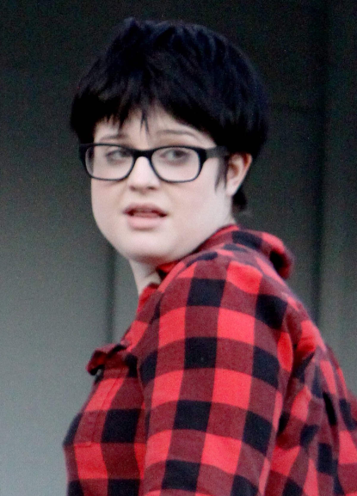 Kelly Osbourne în adolescență într-o cămașă roșie cu carouri negre și cu ochelari
