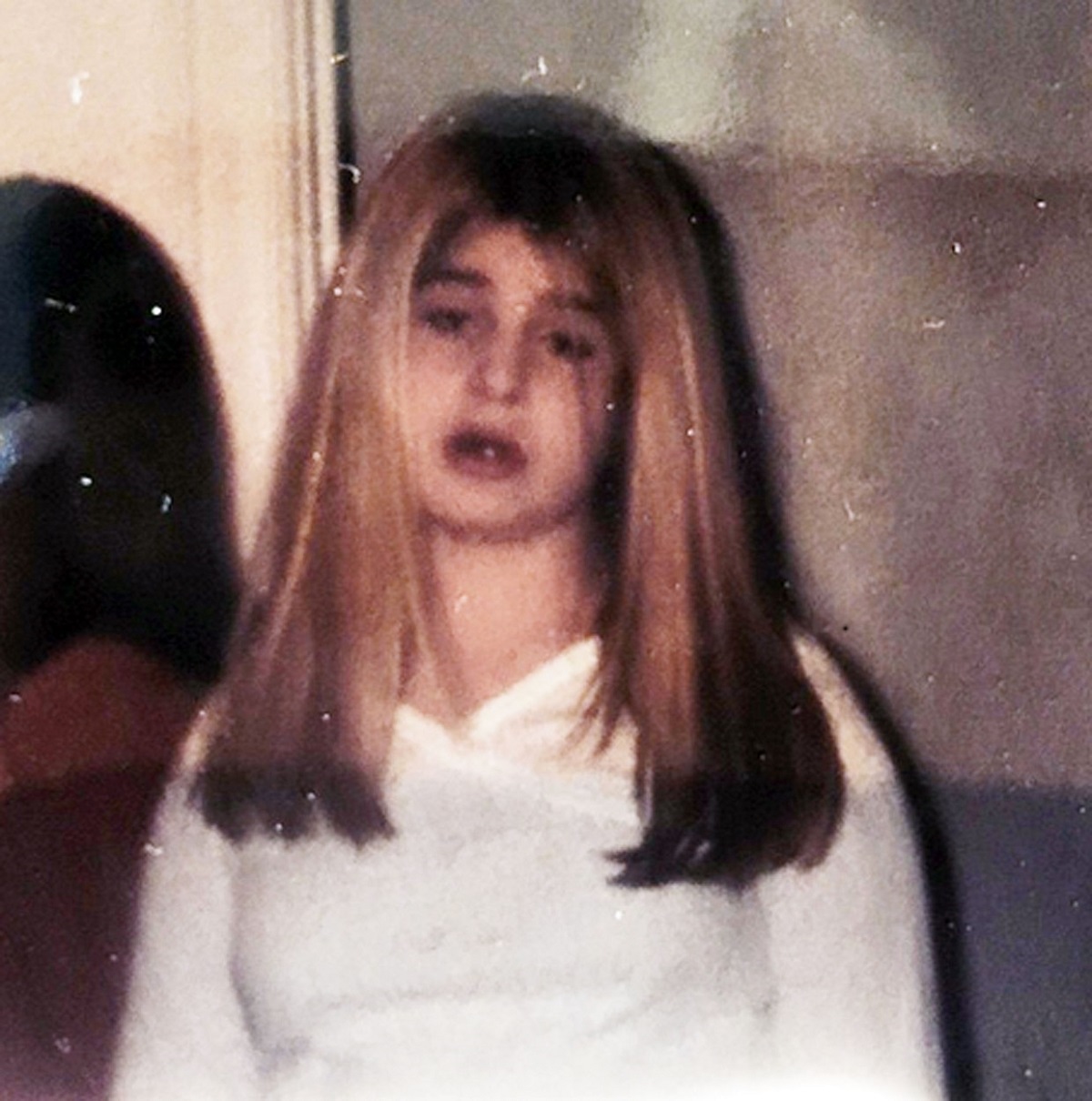 Kelly Osbourne într-o bluză albă cu părul lung și blond în copilărie
