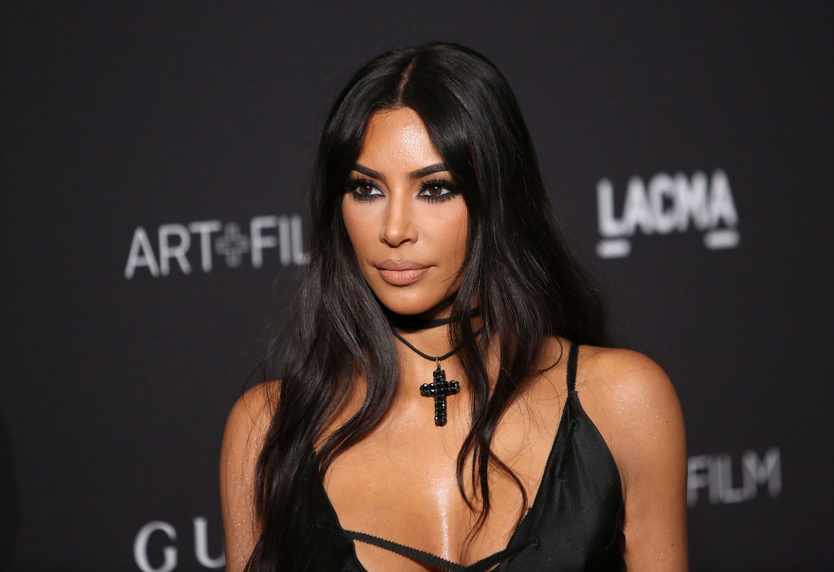 Kim Kardashian într-o rochie neagră cu un lănțisor negru la gât în timp ce pozează pe covorul roșu
