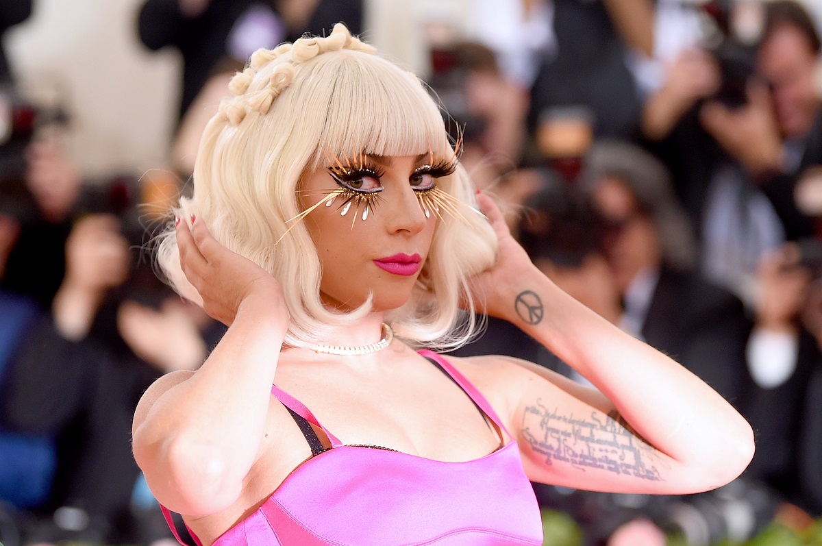 Lady Gaga cu părul blond și o rochie roz în timp ce pozează pe covorul roșu la Met Gala