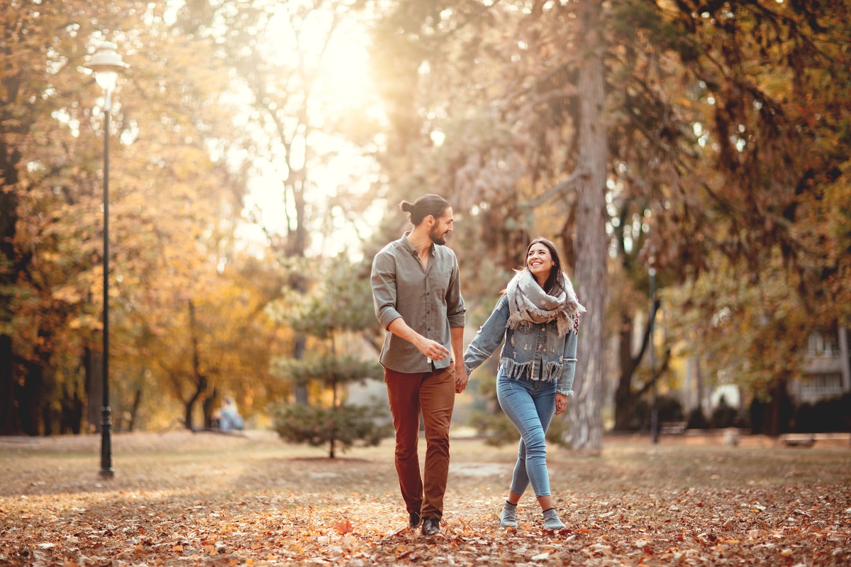 Un cuplu de îndrăgostiți care se țin de mână și se plimbă într-un parc din București toamna