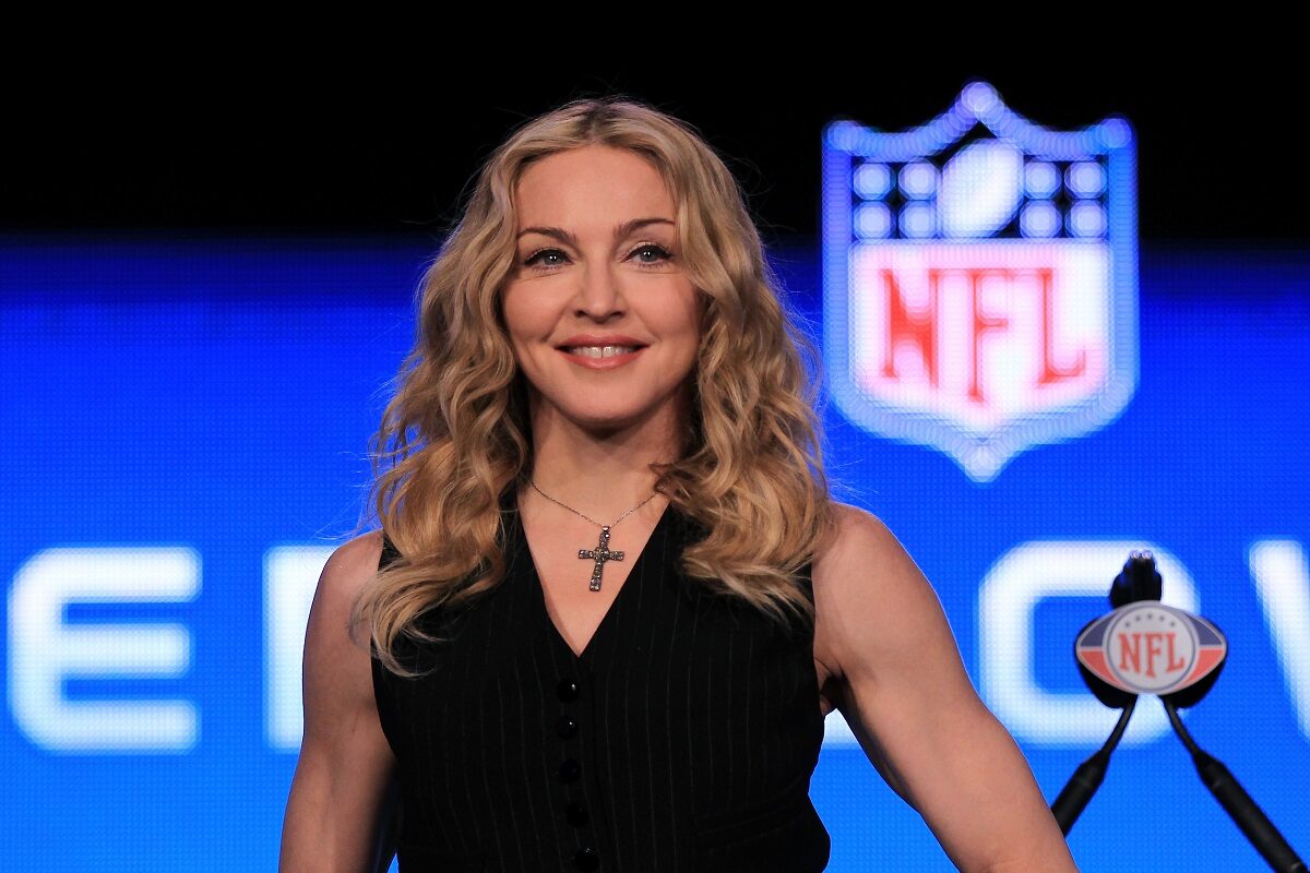 Madonna într-o bluză neagră pe scenă în fața unui microfon