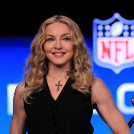 Madonna într-o bluză neagră pe scenă în fața unui microfon