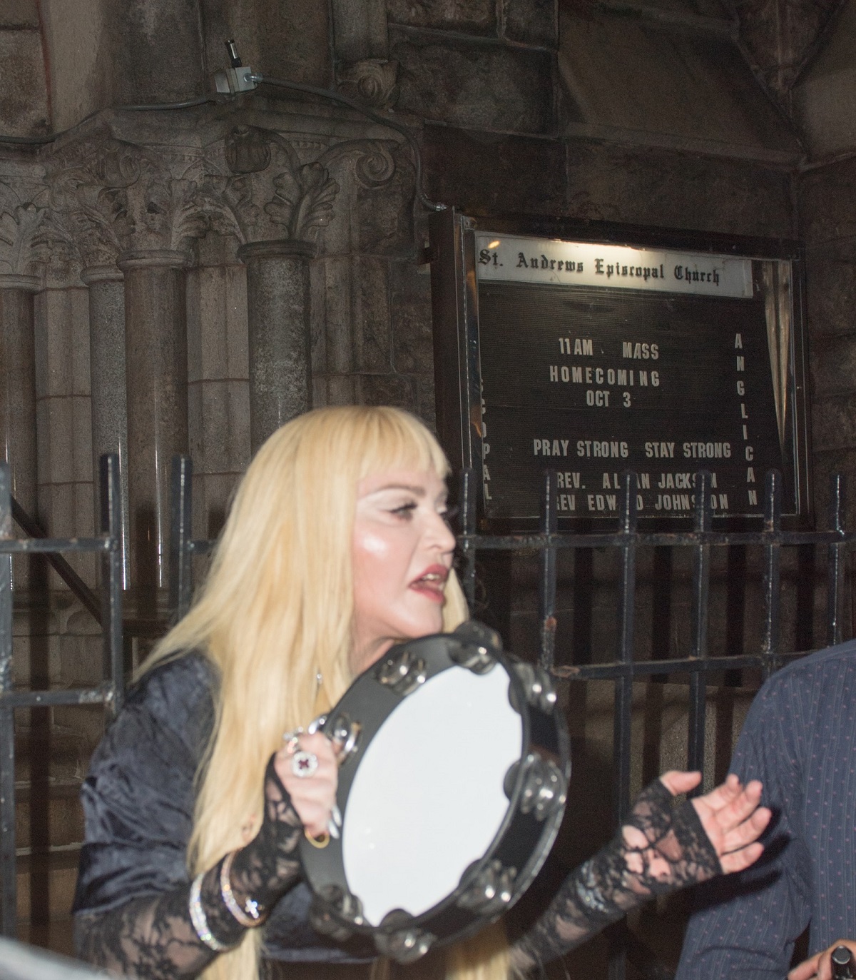 Madonna în fața unei biserici în timp ce cântă la o tamburină