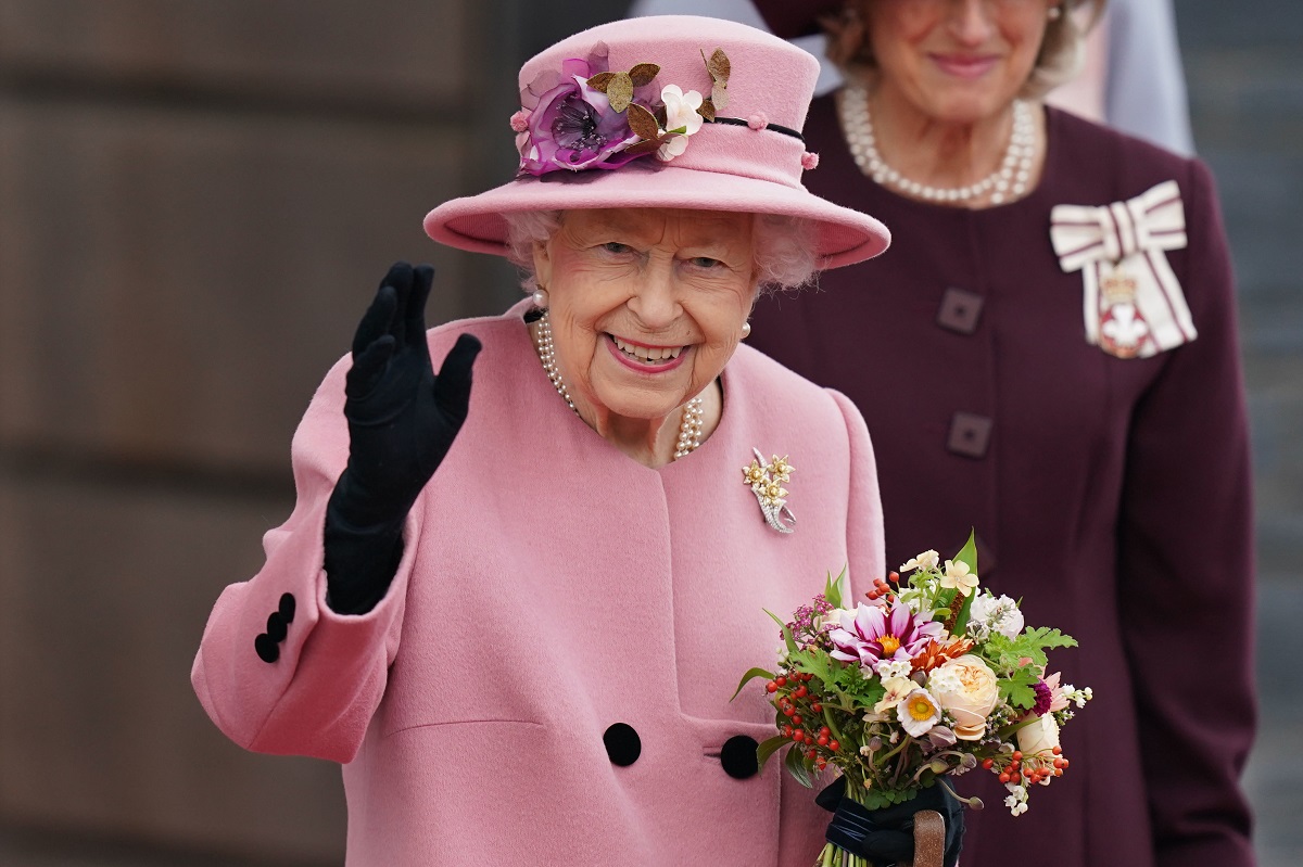 Regina Elisabeta într-un costum roz în timp ce ține în mâini un buchet de flori înainte de momentul în care a fost internată la spital