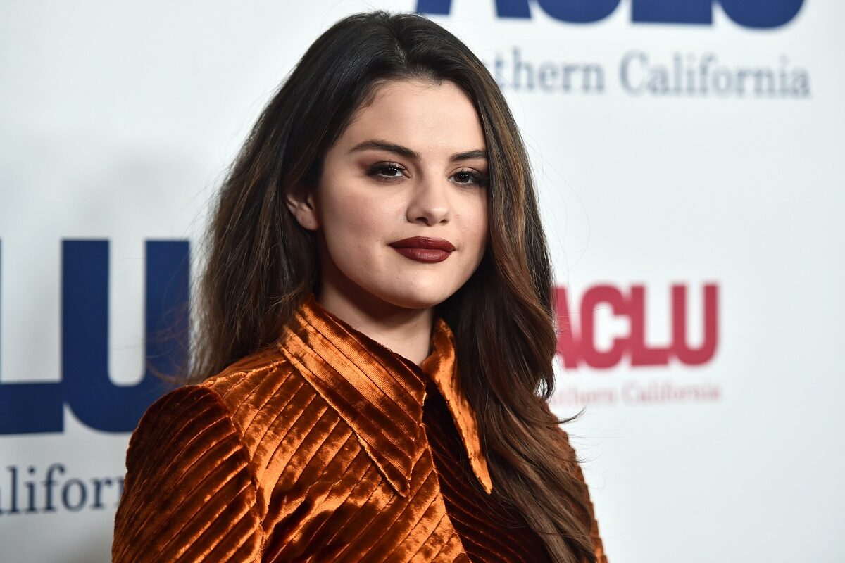 Selena Gomez cu părul desfăcut și cu un ruj maro în timp ce pozează pe covorul roșu