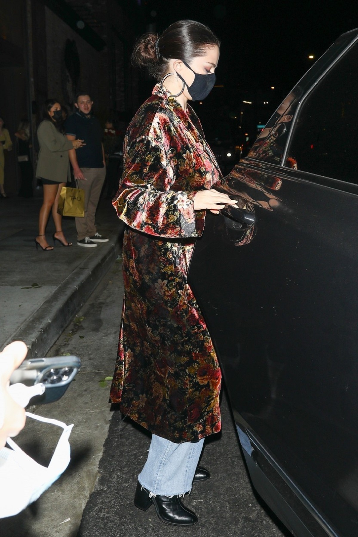 Selena Gomez care a purtat un palton cu imprimeu floral și o pereche de blugi mom fit în timp ce urcă într-o mașină neagră