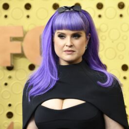 Kelly Osbourne într-o rochie neagră cu părul violet prins într-o codiță