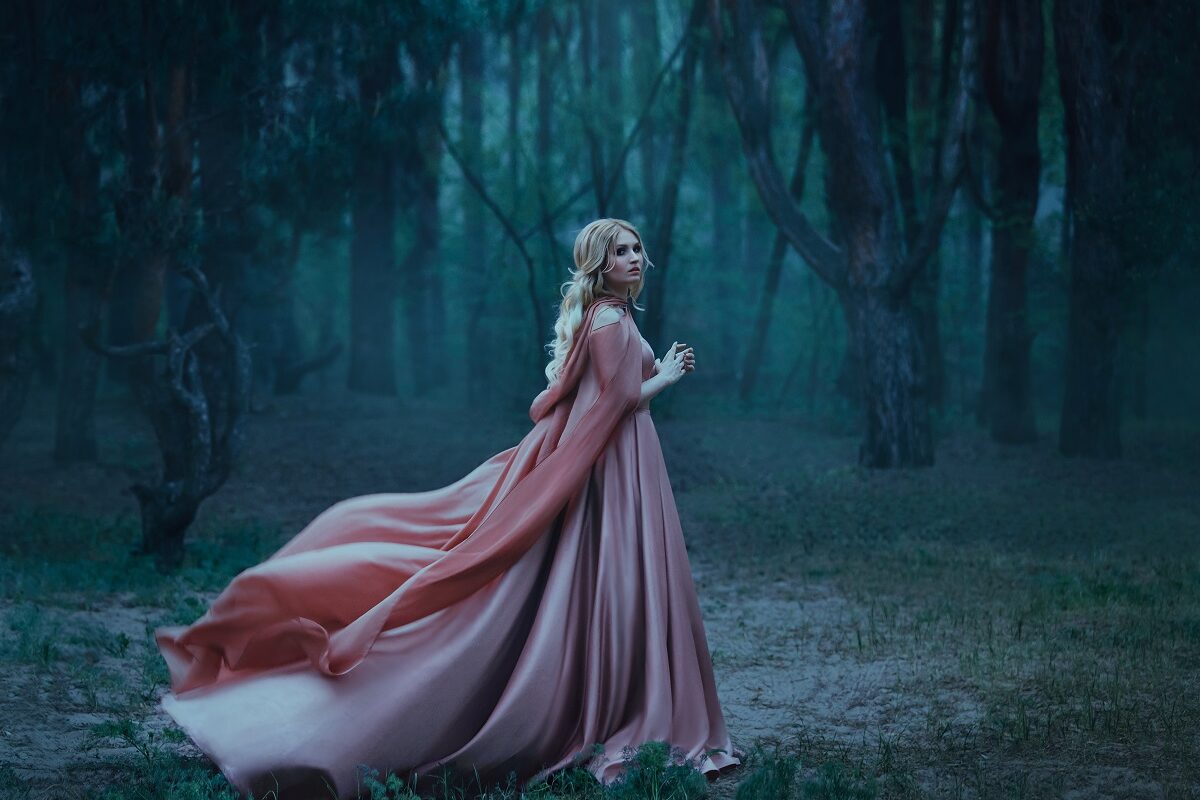 O femeie frumoasă care poartă o rochie roz într-o pădure întucenactă în timp ce întruchipează una din acele zodii ghinioniste în ziua de 7 octombrie 2021