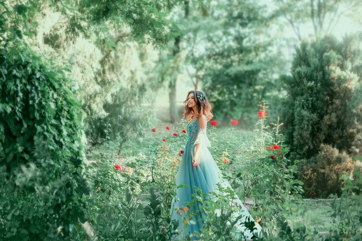 o femeie frumoasă care poartă o rochie albastră și stă în pădure pe un câmp înconjurat cu flori în timp ce este una dintre cele trei zodii norocoase în ziua de 5 octombrie 2021