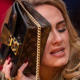Adele, fotografiată în timp ce ține geanta în față și se ferește de fotografi