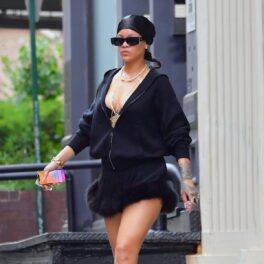 Artista Rihanna într-o fustă scurtă cu blană și un hanorac negru în timp ce merge pe străzile din New York