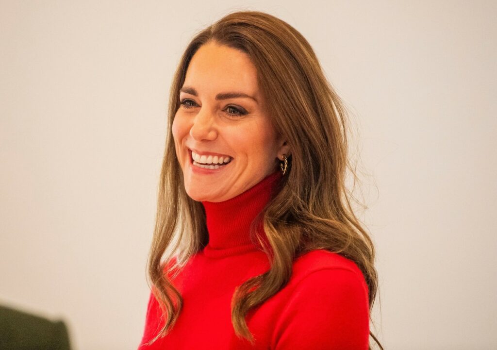 Kate Middleton, fotografie portret, într-o maletă roșie, în timp ce zâmbește
