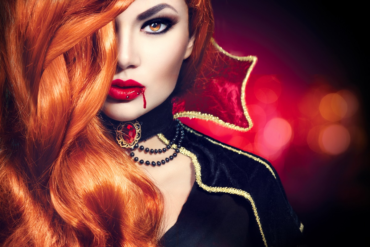 O femeie roșcată cu unul din acele machiaje de Halloween de vampir