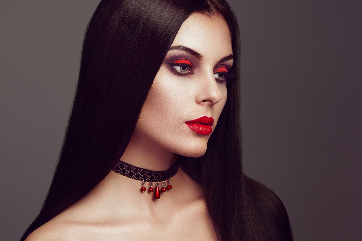 O femeie frumoasă cu părul lung și brunet în timp ce însățișează un vampir de Halloween