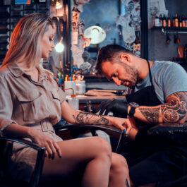 O femeie care își face un tatuaj pe braț, la salon