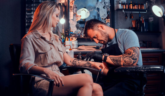 O femeie care își face un tatuaj pe braț, la salon