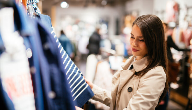 O femeie care se uită la hainele expuse într-un magazin