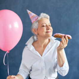 O femeie după 50 de ani care mănâncă un ecler în timp ce sărbătorește ceva