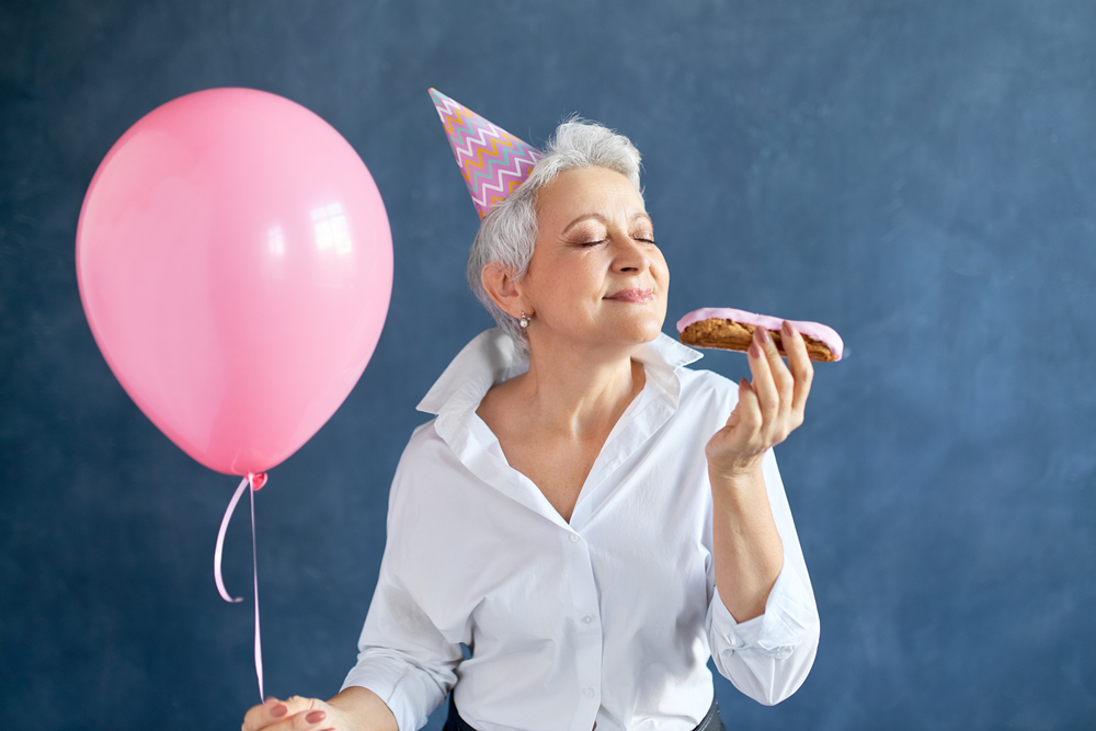 O femeie după 50 de ani care mănâncă un ecler în timp ce sărbătorește ceva