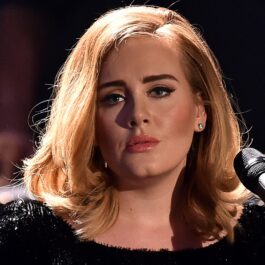 Adele într-o rochie neagră în fața unui microfon în timpul unui concert din Berlin din 2015