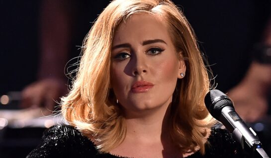 Adele într-o rochie neagră în fața unui microfon în timpul unui concert din Berlin din 2015