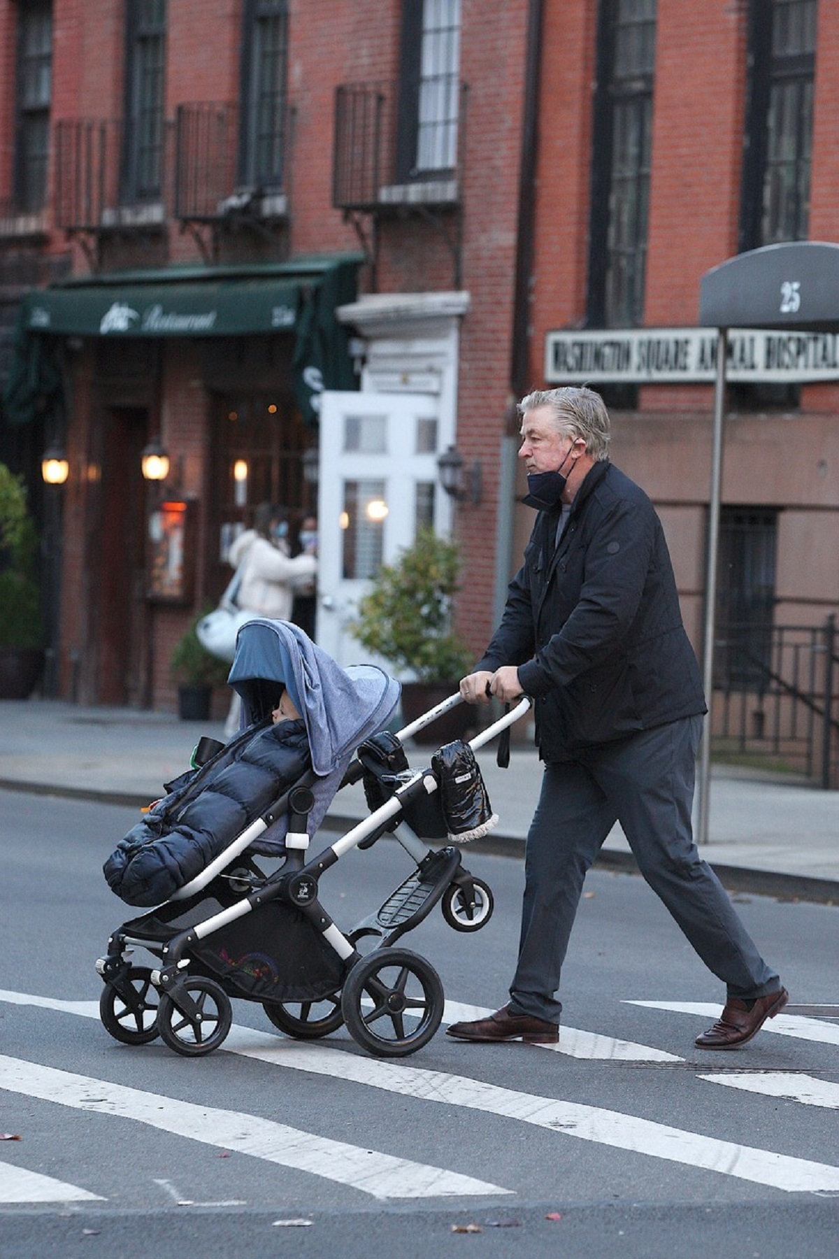 Alec Baldwin împingând la căruciorul copilului său pe o trecere de pietoni din New York
