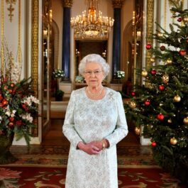 Regina Elisabeta într-o rochie albă de sărbătoare alături de doi brazi împodobiți de Crăciun în anul 2012