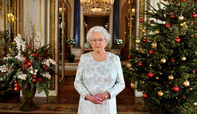 Regina Elisabeta într-o rochie albă de sărbătoare alături de doi brazi împodobiți de Crăciun în anul 2012