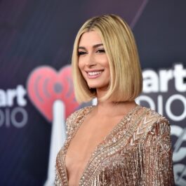 Hailey Bieber cu părul scurt și blond într-o rochie cu decolteu adânc în timp ce pozează pe covorul roșu la iHeart Radio Music Awards din 2018