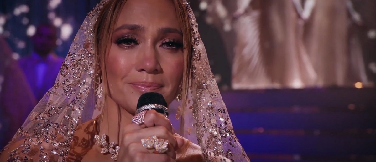Jennifer Lopez, machiată, cu un microfon în mână, imagini din comedia Marry Me