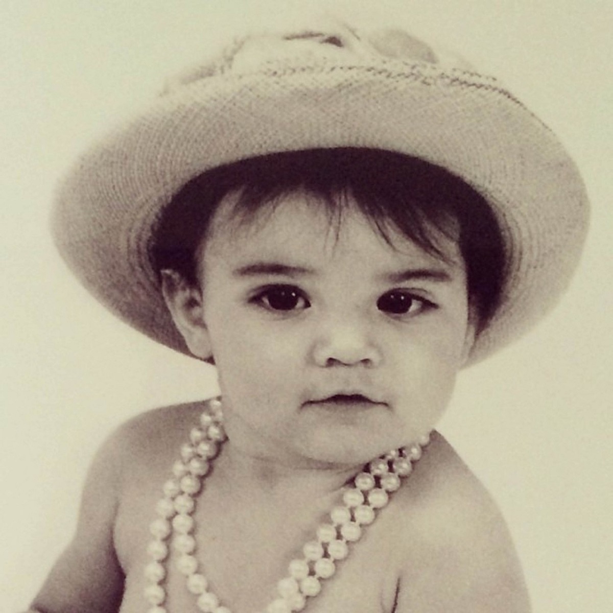 Kendall Jenner când era bebeluș cu o pălăriuță pe cap și mărgele la gât