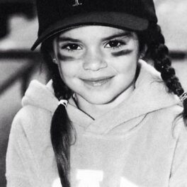 Kendall Jenner cu codițe, șapcă și două dungi desenate sub ochi într-o fotografie alb negru din copilărie