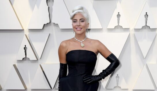 Lady Gaga într-o rochie neagră mulată cu o pereche de mănuși lungi pe covorul roșu la Premiile Oscar din 2019