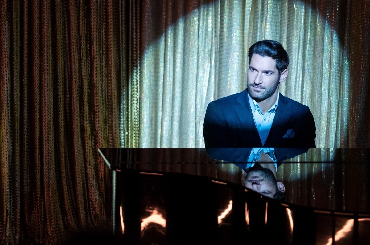 Tom Ellis în costum negru în timp ce cântă la pian în serialul Lucifer