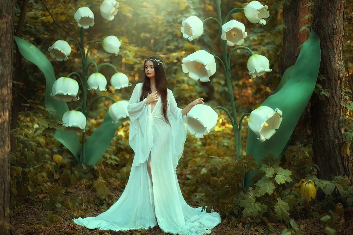 O femeie frumoasă într-o rochie albă care stă într-o pădure cu flori de mărgăritar pentru a înfățișa una dintre cele trei zodii norocoase în ziua de 20 noiembrie 2021