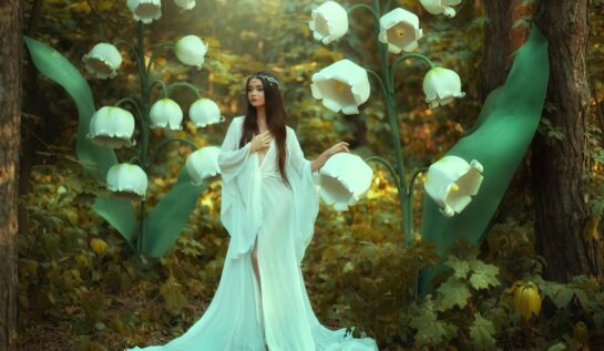 O femeie frumoasă într-o rochie albă care stă într-o pădure cu flori de mărgăritar pentru a înfățișa una dintre cele trei zodii norocoase în ziua de 20 noiembrie 2021
