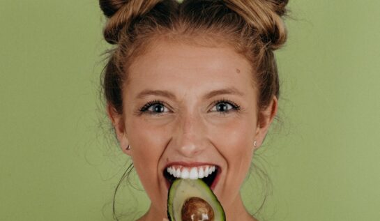 O fată drăguță, care mușcă dintr-un avocado