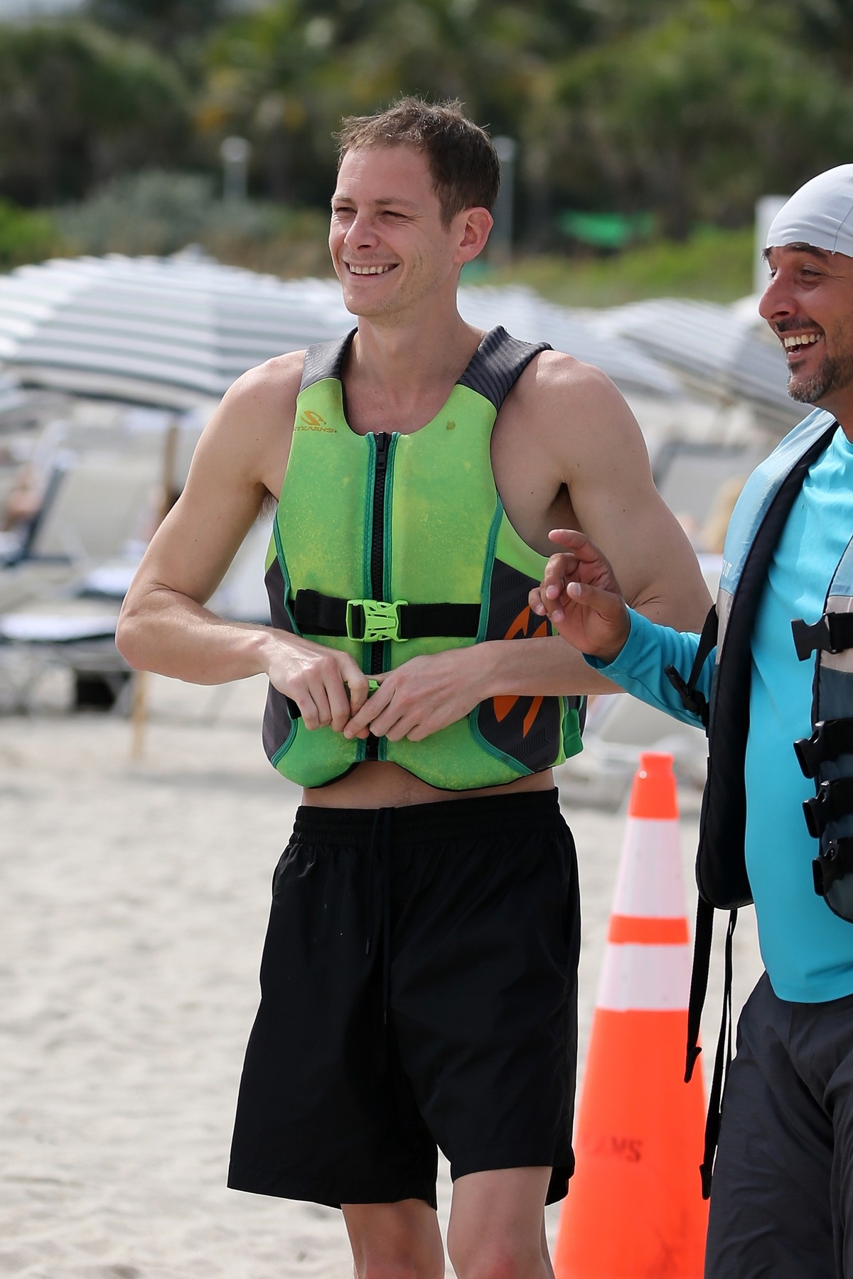 Marc Kalman în pantaloni scurți și o vestă de salvare verde pe plajă în Miami