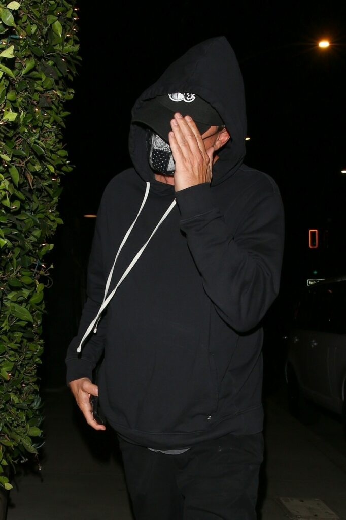 Leonado DiCaprio, cu mâna la față și gluga pe cap, în timp ce se ferește de fotografi