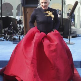 Lady Gaga într-o rochie neagră cu o trenă amplă roșie în timp ce urcă scările de la Capitoliu după ce a cântat imnul național al SUA