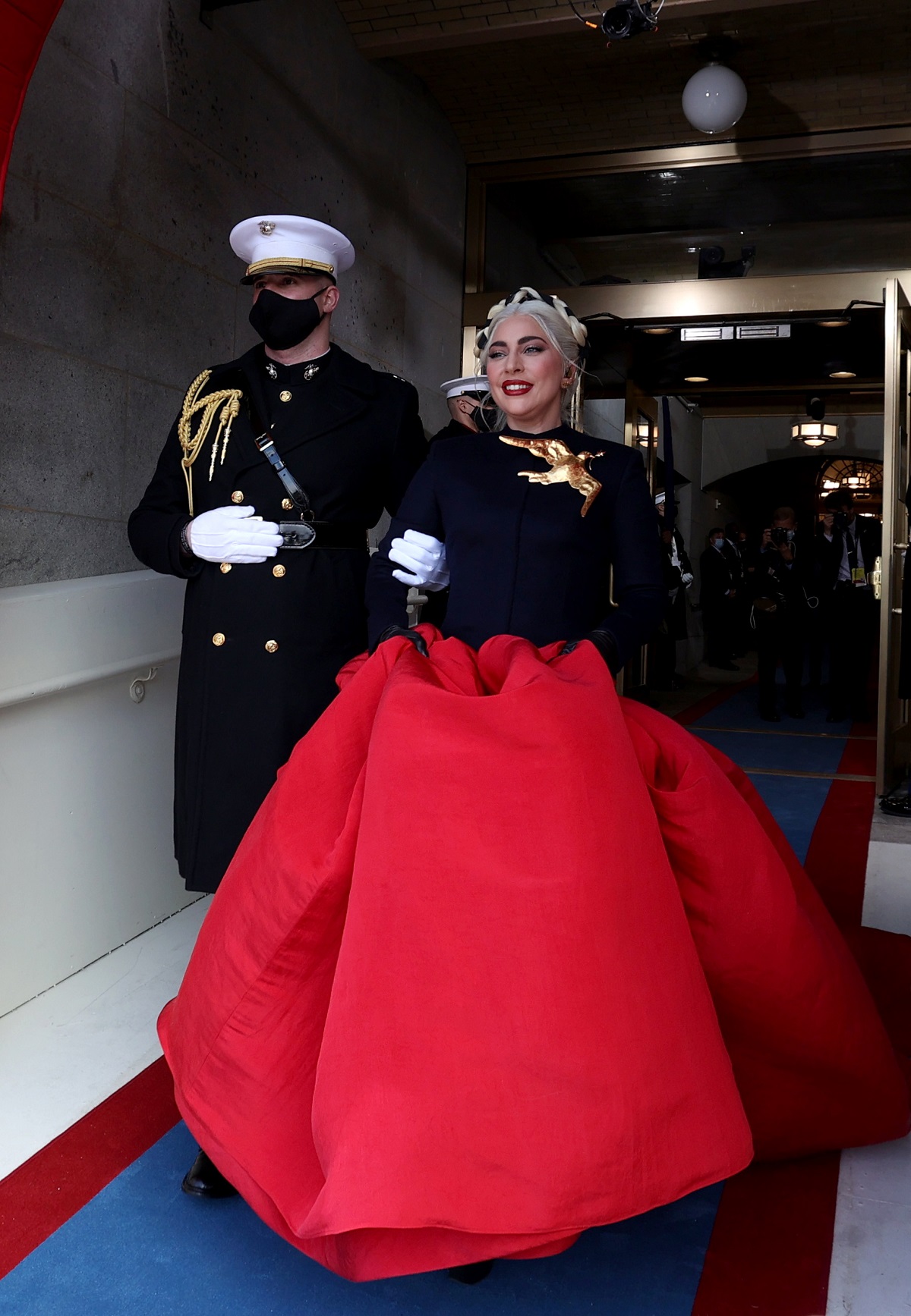 Lady Gaga într-o rochie cu trenă roșie în timp ce urmează să cânte la inaugurarea președintelui Joe Biden