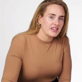 Adele cu părul dat pe spate și o bluză crem în timp ce se pozează nemachiată
